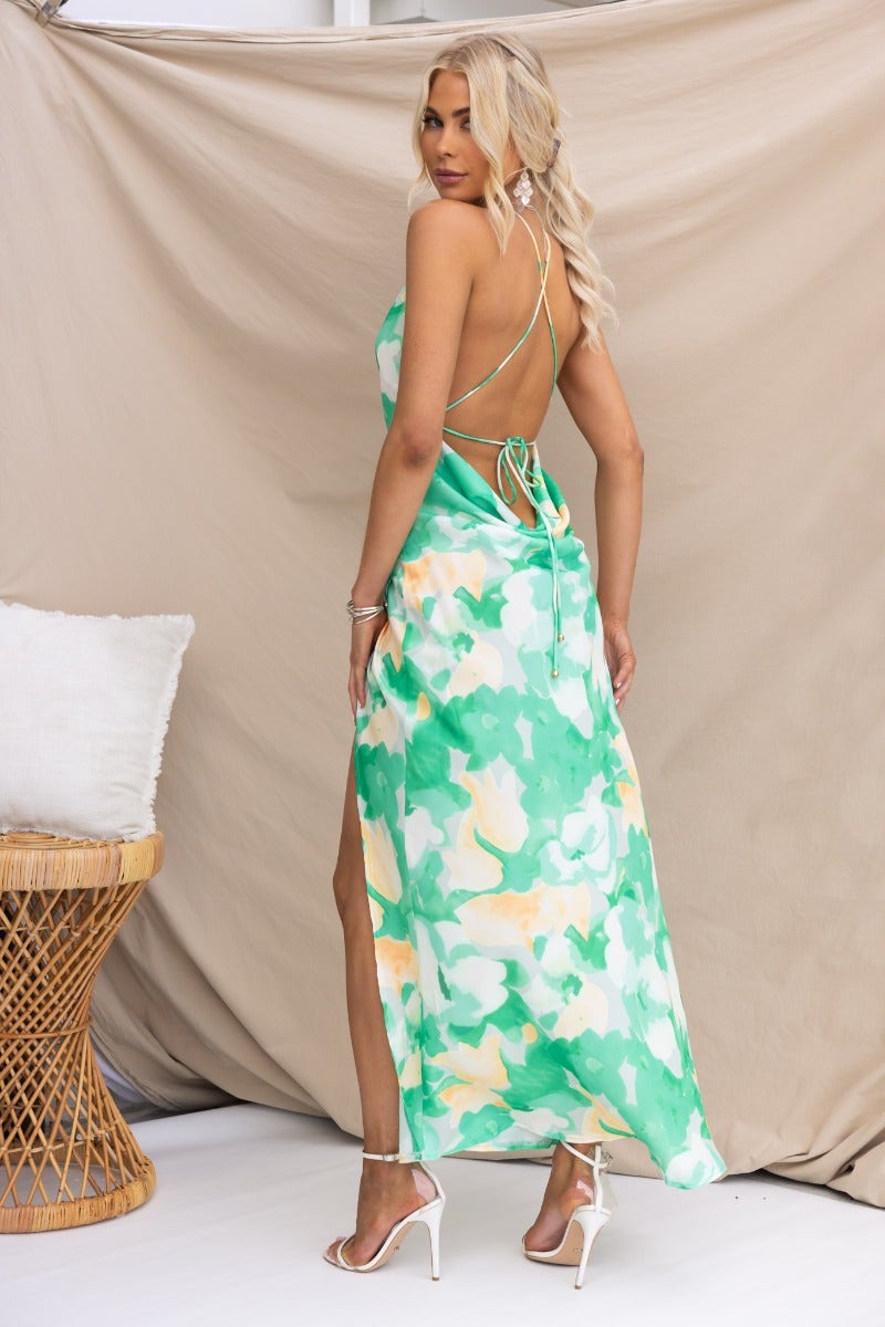 Back view of a floral print Tangelo maxi dress featuring adjustable tie straps and an asymmetrical hemline.