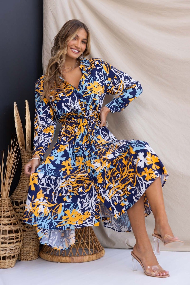 Navy floral midi dress with a collar, button-up front, removable tie, and pockets, styled for a relaxed fit.