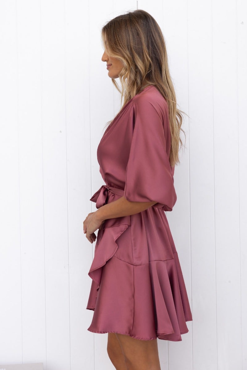 Side view of Xention Dress, a satin dress with V-neckline, batwing sleeves, and removable belt in dusty rose color.