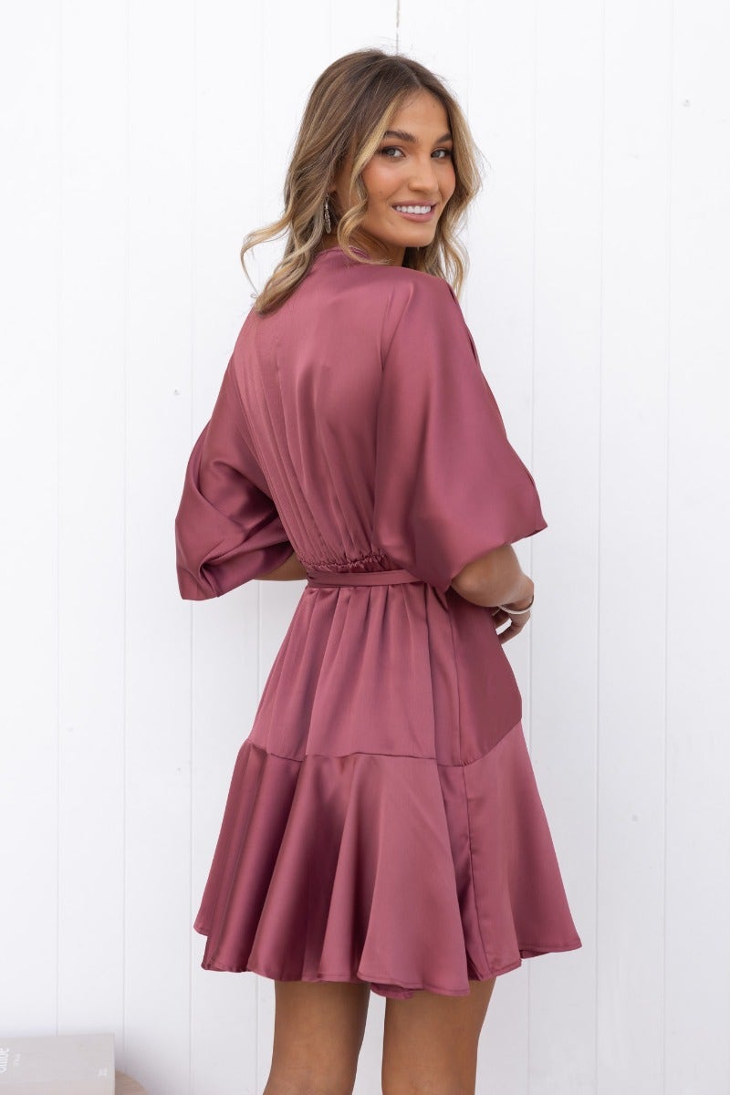 Model wearing a satin Xention dress with batwing sleeves and a flared skirt, showcasing an elegant V-neckline.