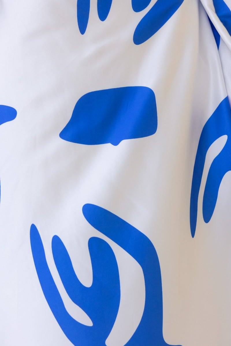 Close-up of Qasim Maxi Dress fabric featuring bold blue abstract designs on a silky white background.