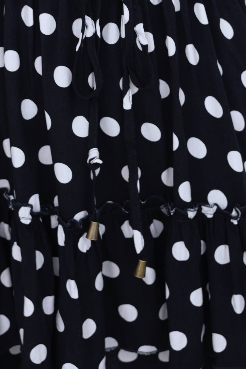 Close-up of navy polka dot dress featuring drawstring waist and elastic cuffs.