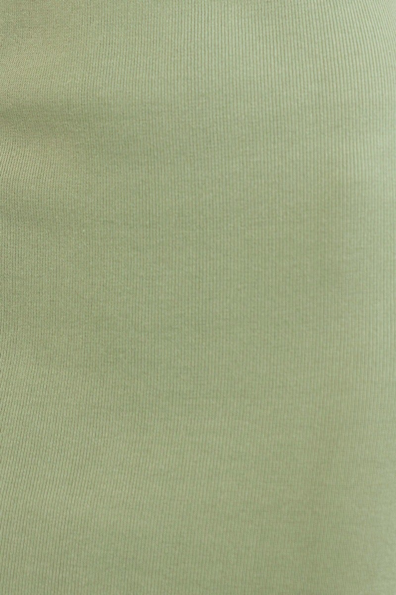 Close-up of ribbed knit fabric in soft green, showcasing its stretchy texture for versatile fashion use.