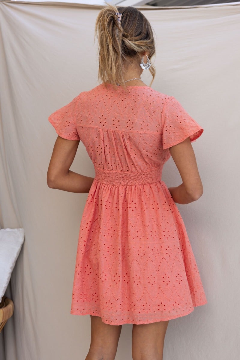 Back view of Udela Dress in Anglaise material, featuring V-neckline and button-up front, in coral color.