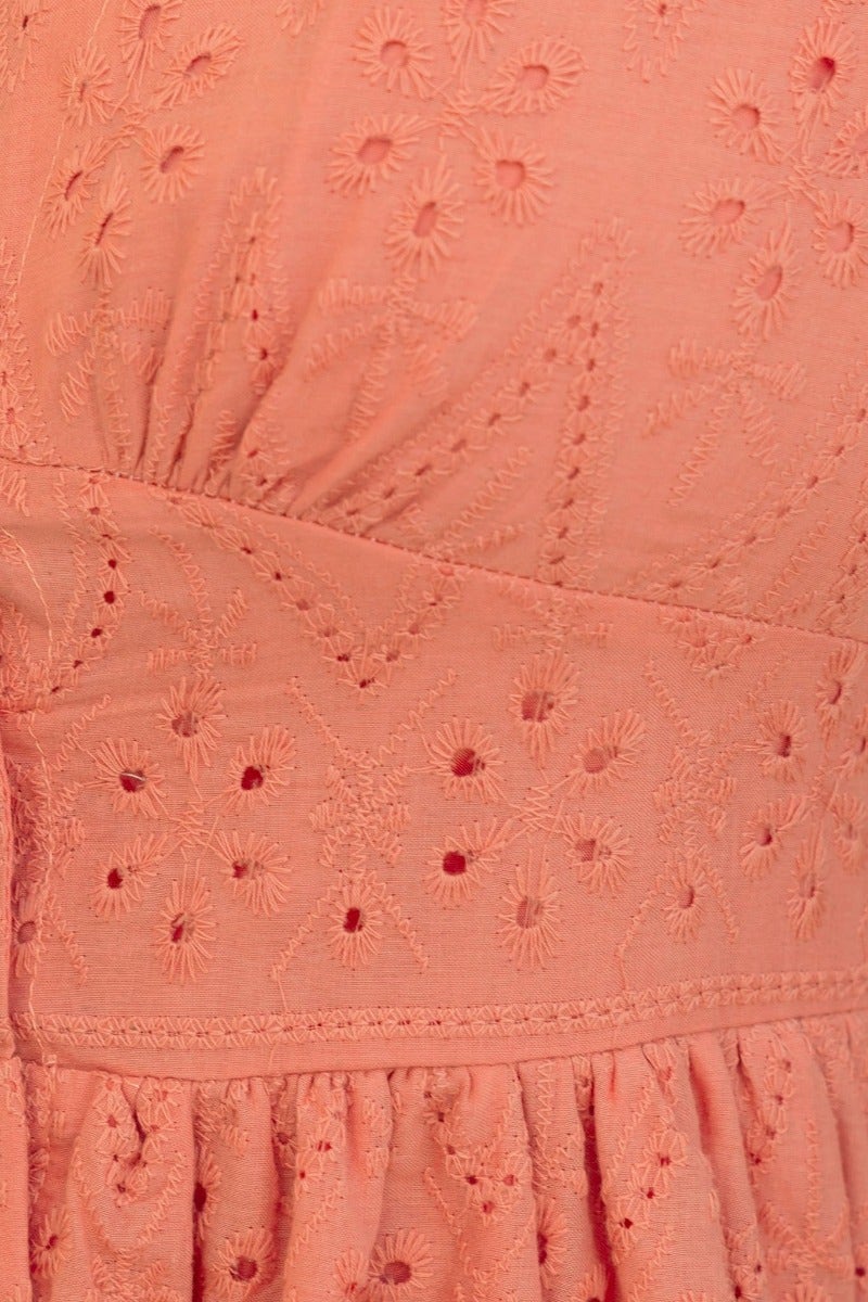 Close-up of Udela Dress featuring intricate Anglaise embroidery in a soft coral color.