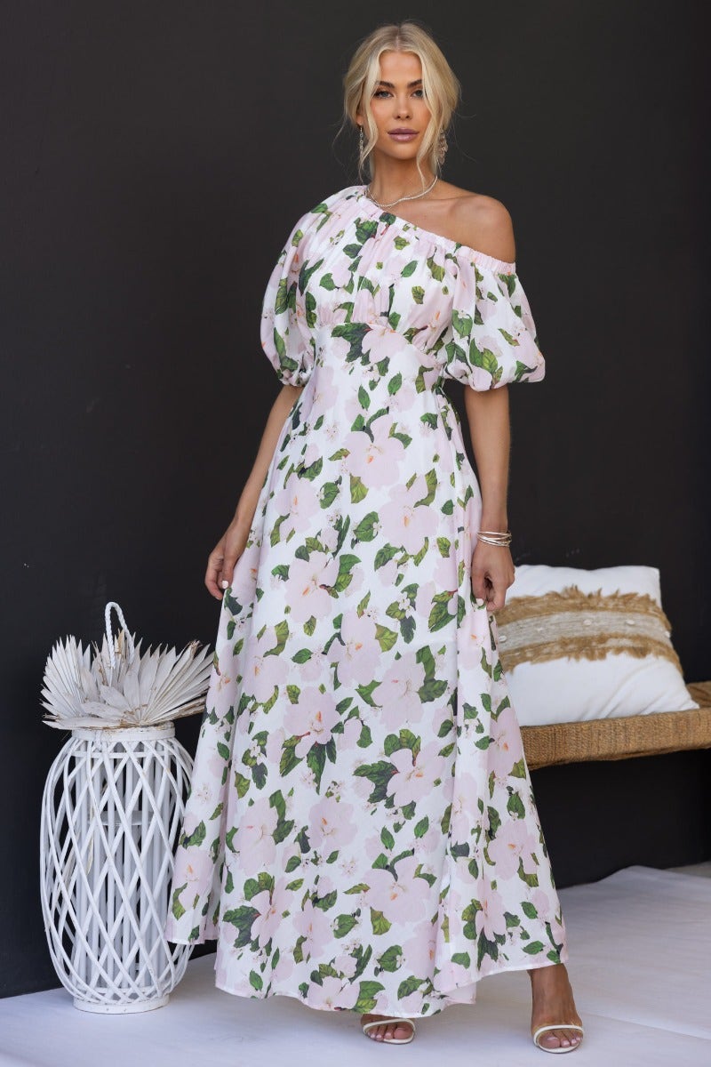 Woman wearing a floral print off-shoulder maxi dress with elastic neckline and sleeve cuffs.