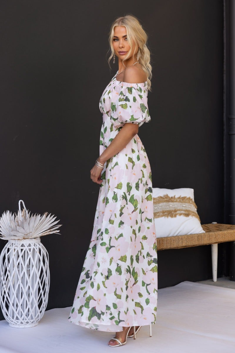Zonnie maxi dress featuring floral print, off-shoulder neckline, and elastic cuffs, model wearing size XS.
