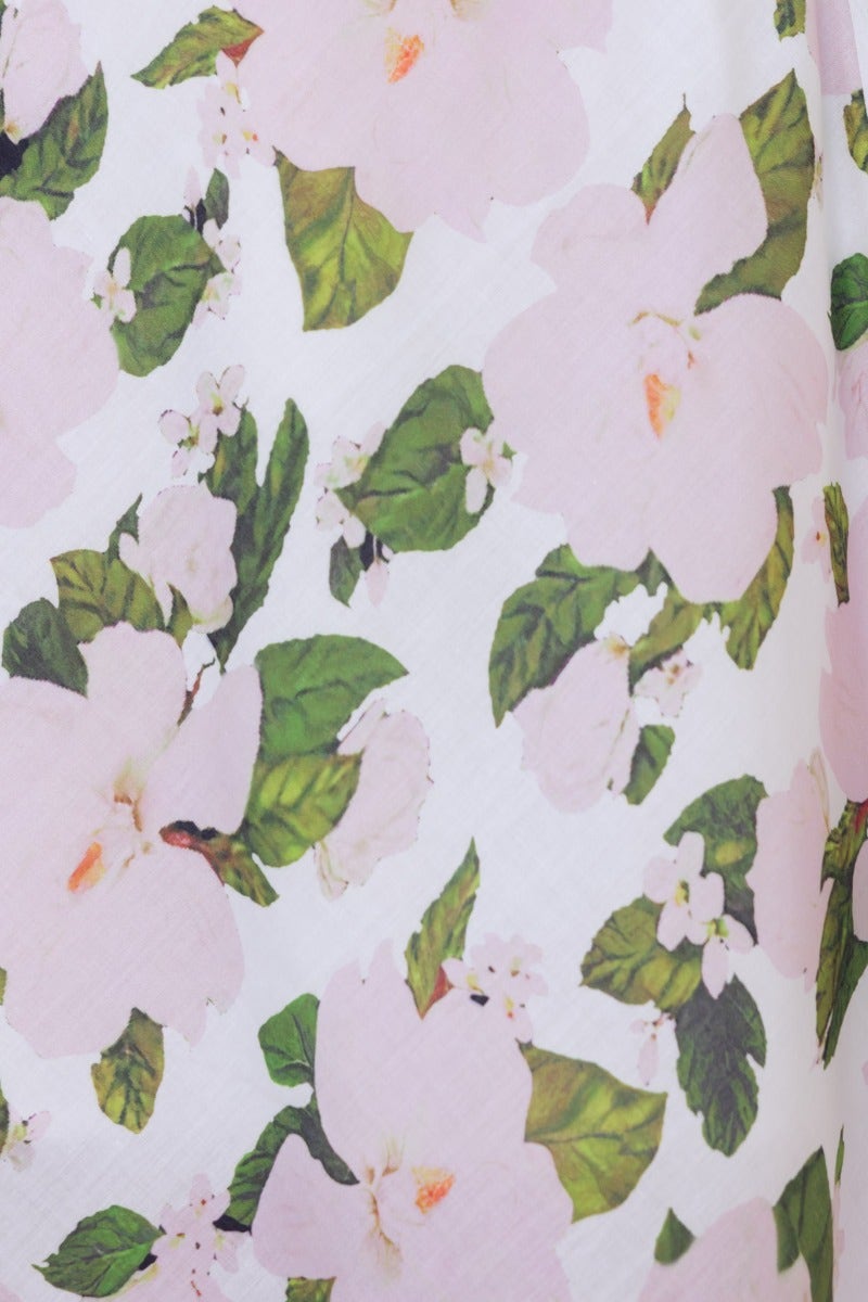 Floral print detail of the Zonnie Maxi Dress featuring pink flowers and green leaves on a white background.