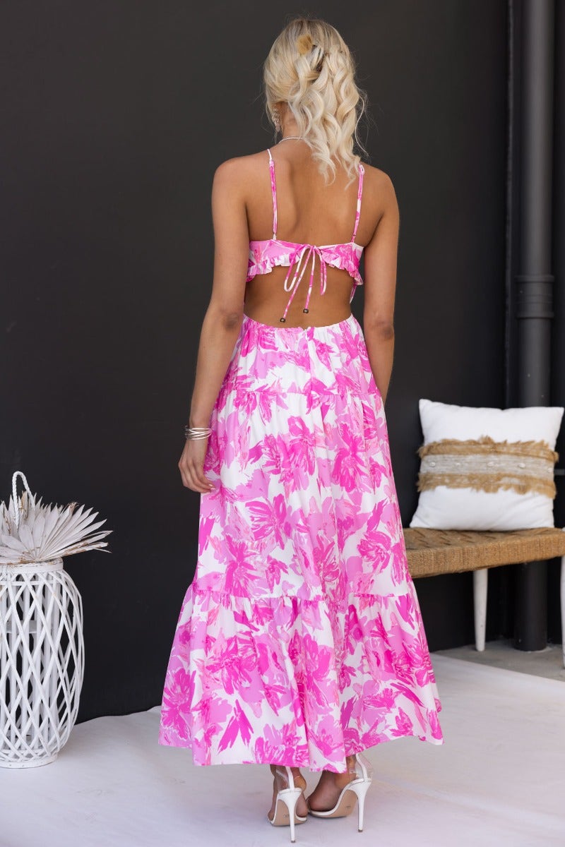 Back view of a pink floral print maxi dress with adjustable straps and tie detail, styled for a summer look.