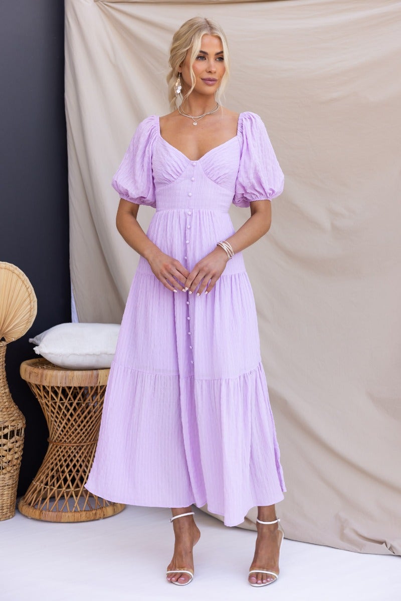 Nammos Maxi Dress in lilac with puff sleeves and button-up front, styled elegantly, perfect for summer occasions.