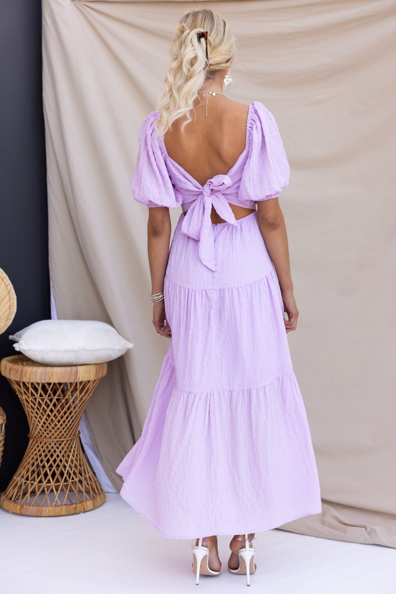 Back view of Nammos Maxi Dress in lavender, featuring puff sleeves, tied back, and a flowing tiered skirt.