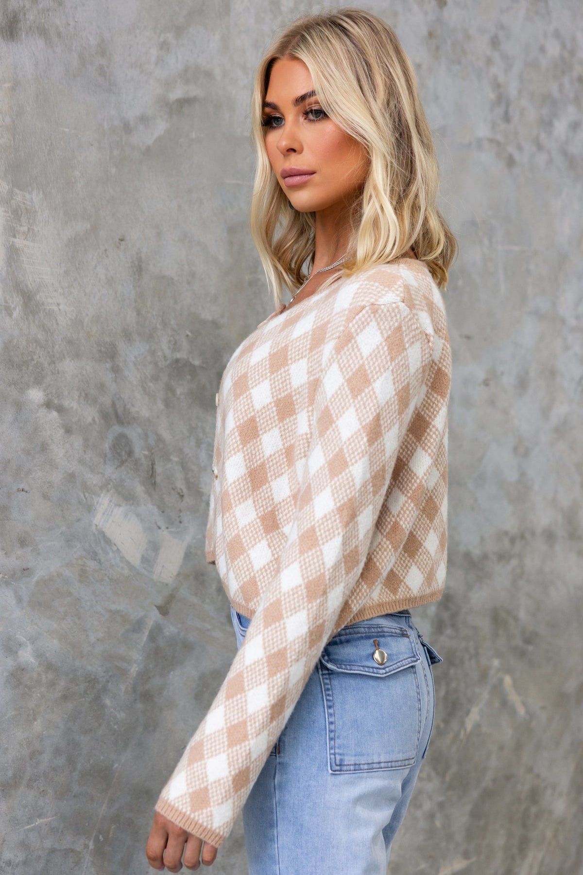 Model wearing Addie Cardigan with round neckline, button-up front, and cream checkered pattern, styled with denim.