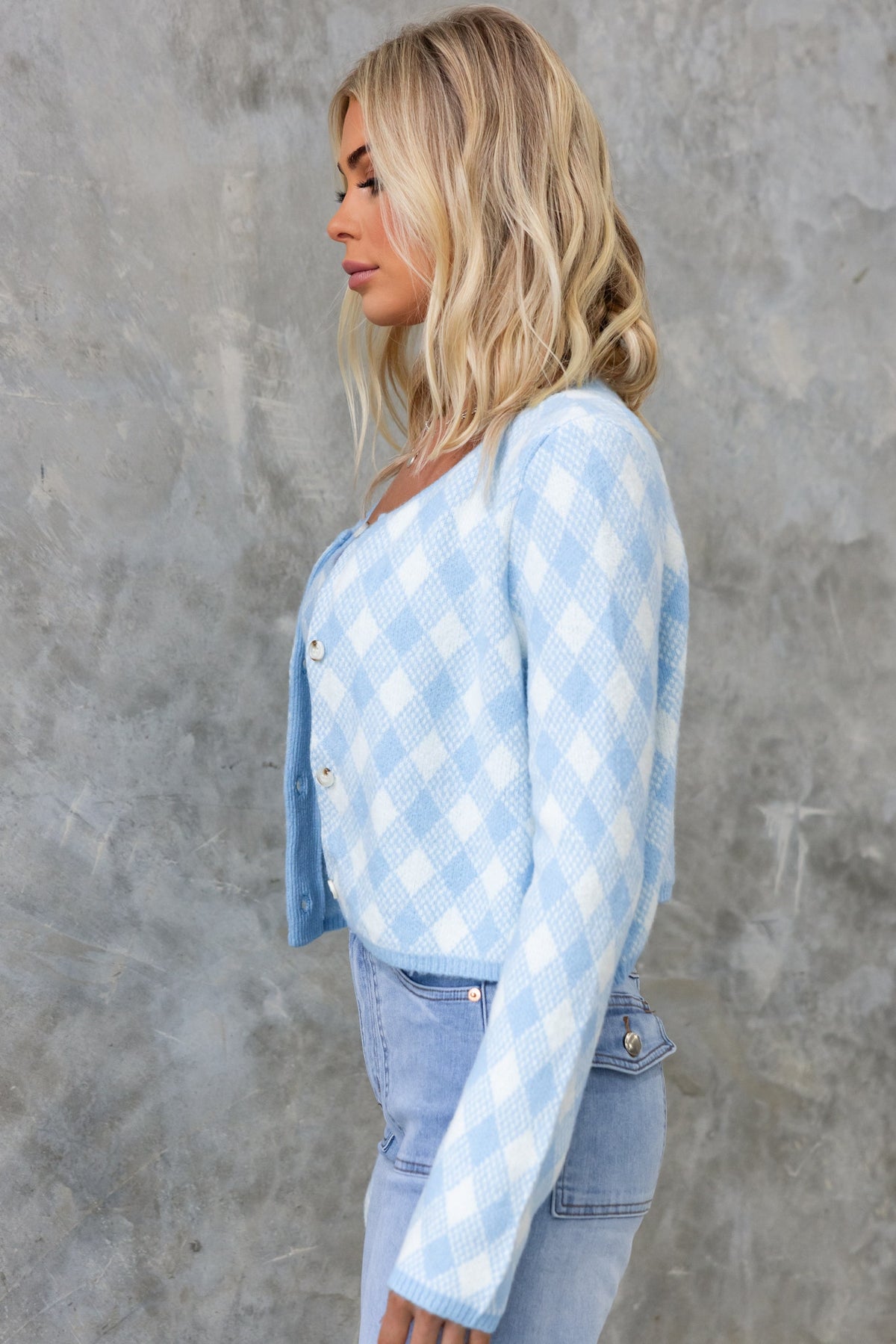 Side view of a woman in a blue and white checkered Addie Cardigan with a round neckline and button-up front.