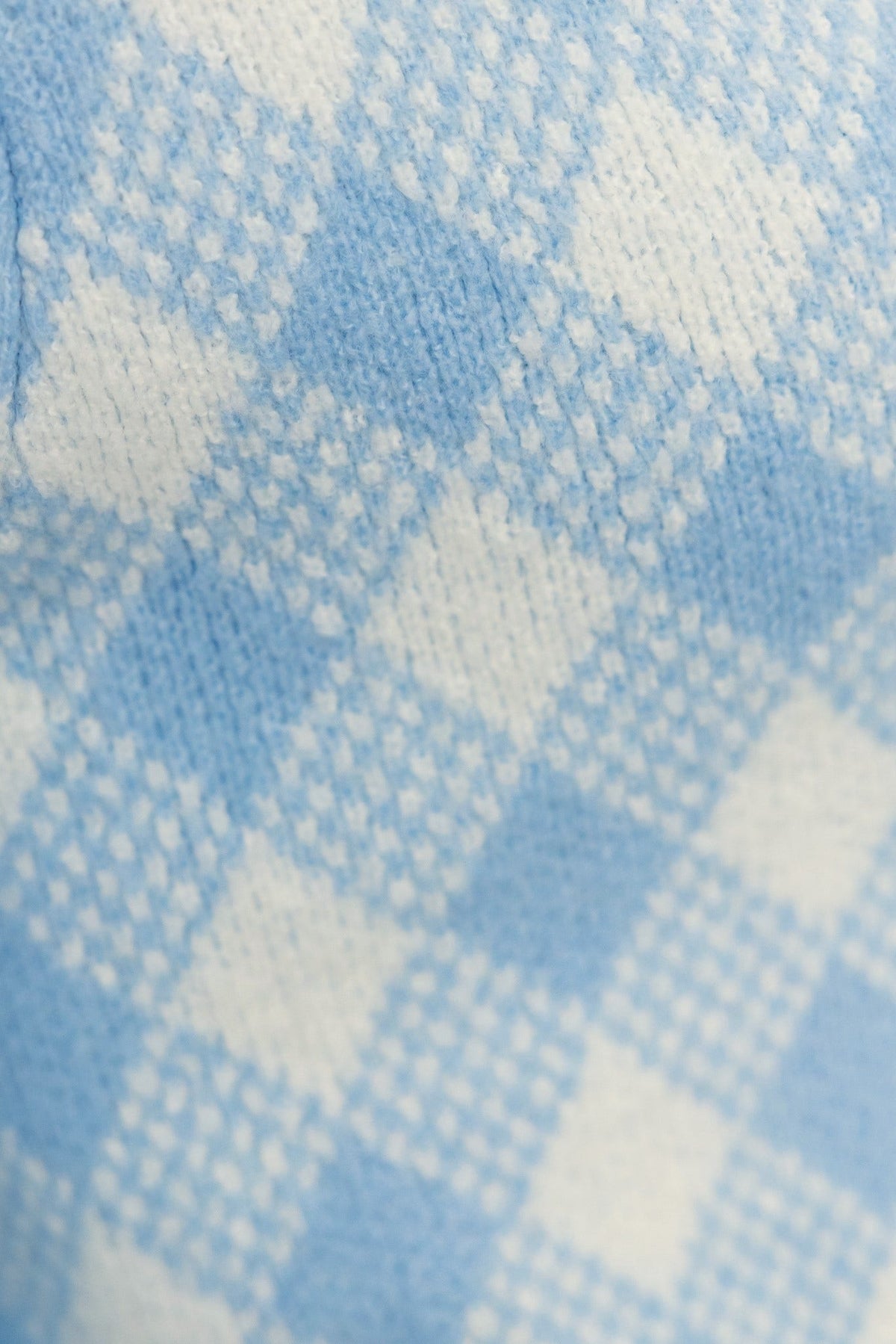 Close-up of blue and white checkered knit fabric, showcasing texture and pattern typical of stylish cardigans.