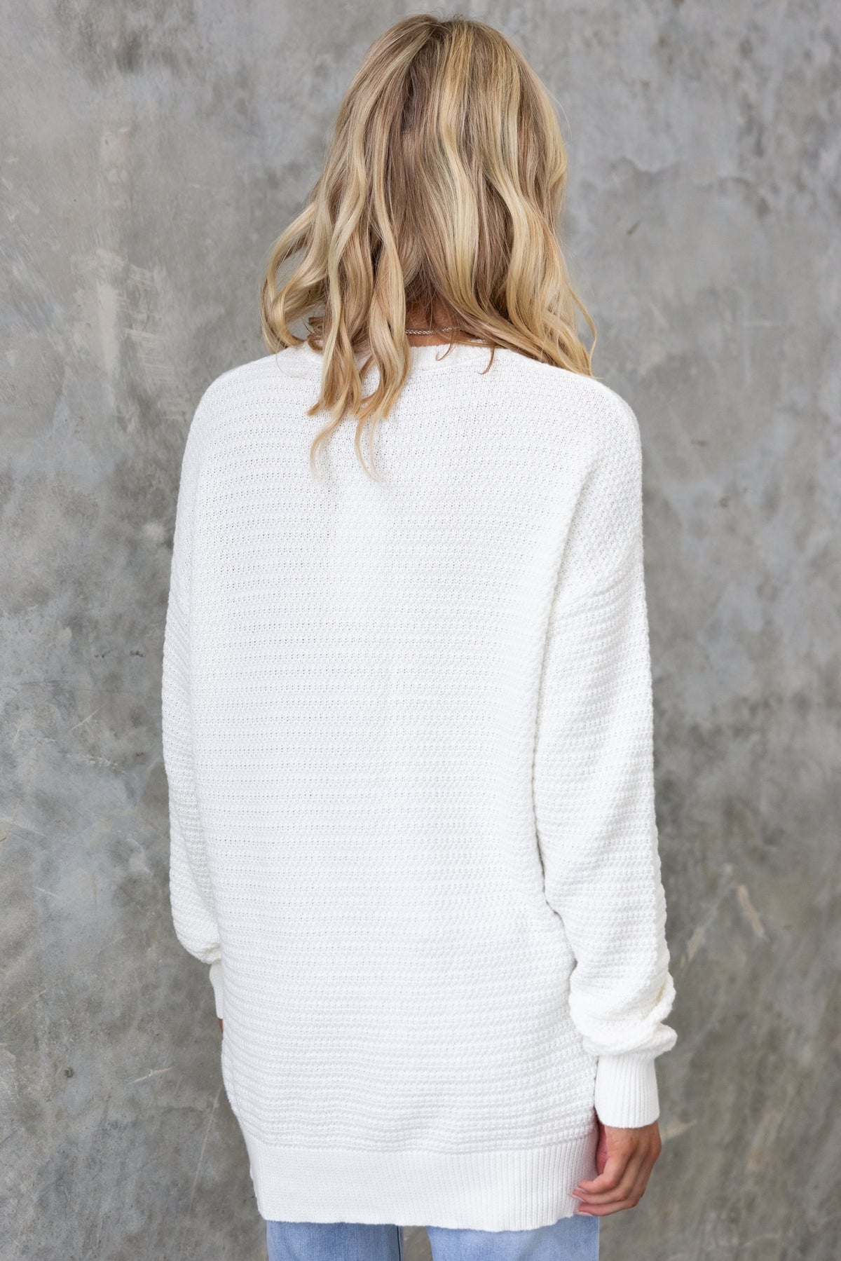 Back view of a model wearing a cozy white knit Rhode Jumper, showcasing its relaxed fit and round neckline.