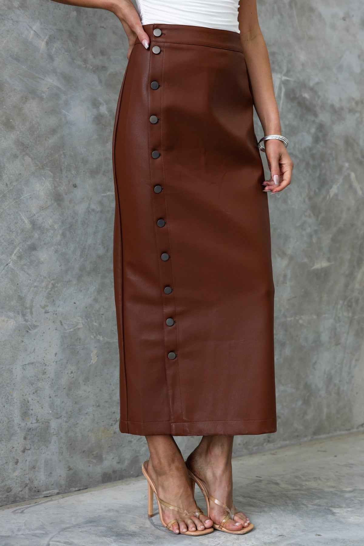 Brown faux leather maxi skirt with button-up front, styled for a chic, casual look.