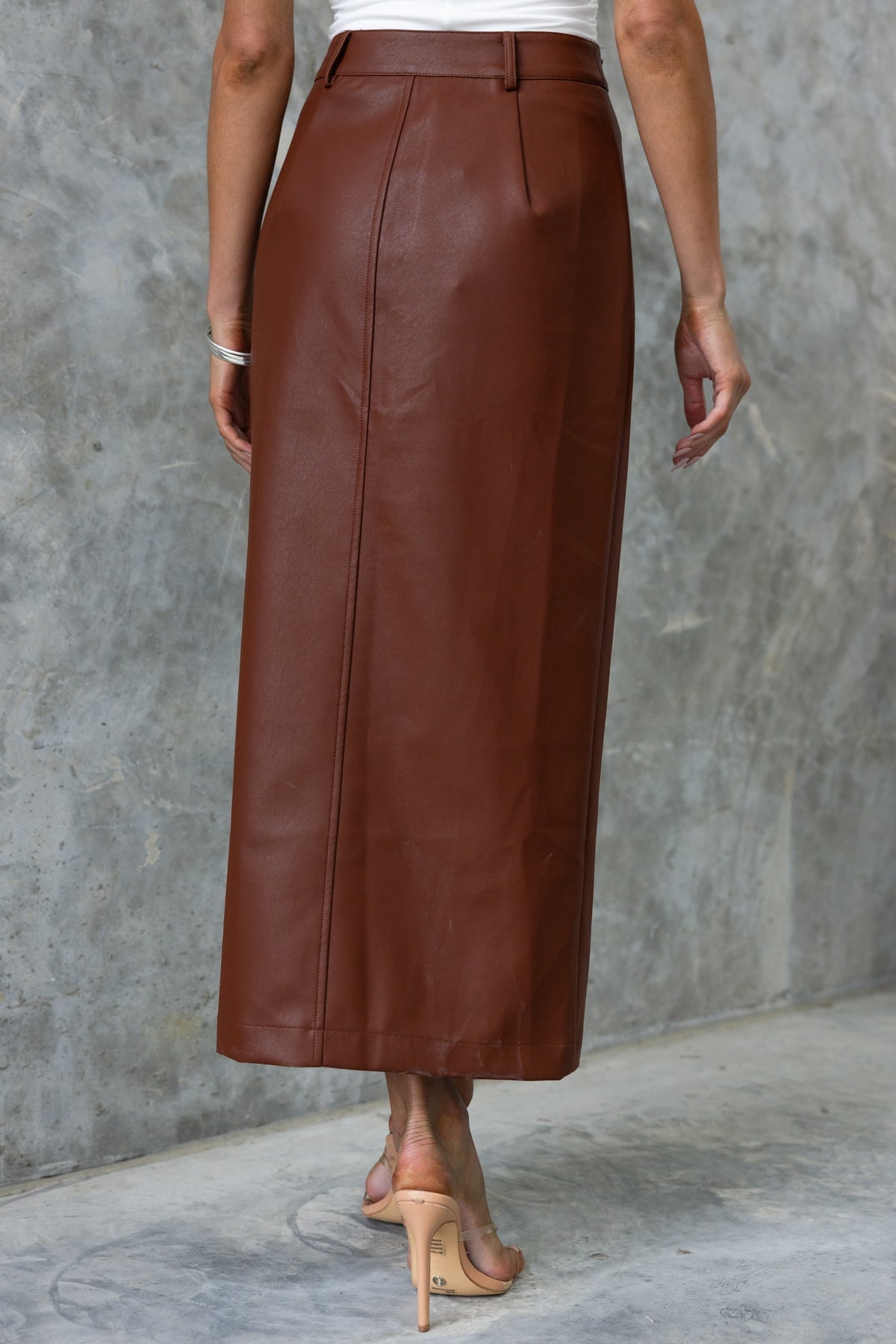 Back view of a brown faux leather maxi skirt with a high waist and sleek design, perfect for stylish outfits.