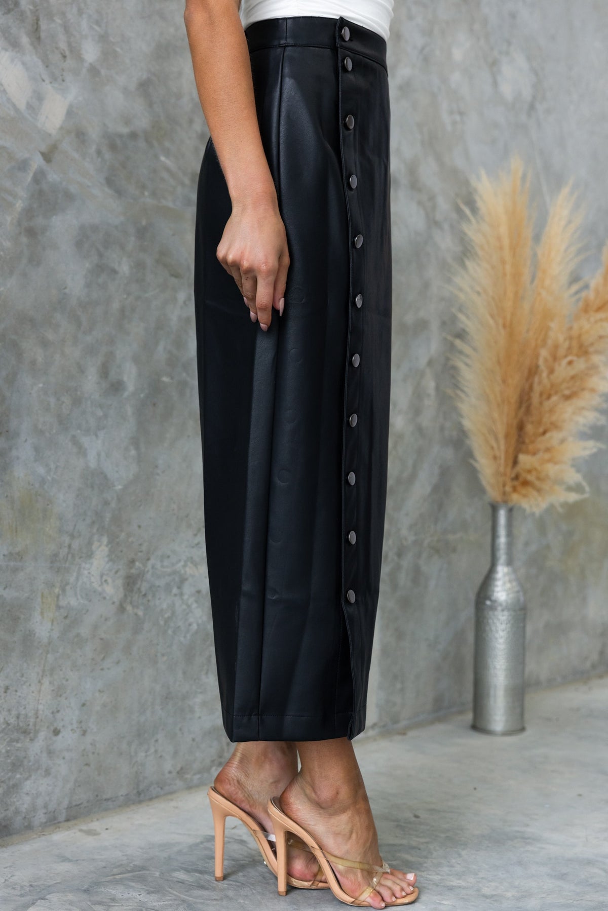 Black faux leather maxi skirt with button-up front, mid-high waist, styled with nude heels.