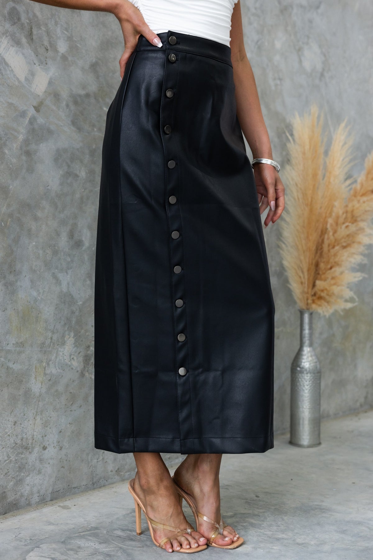 Black faux leather maxi skirt with button-up front, featuring a mid-high waist and stretch material.