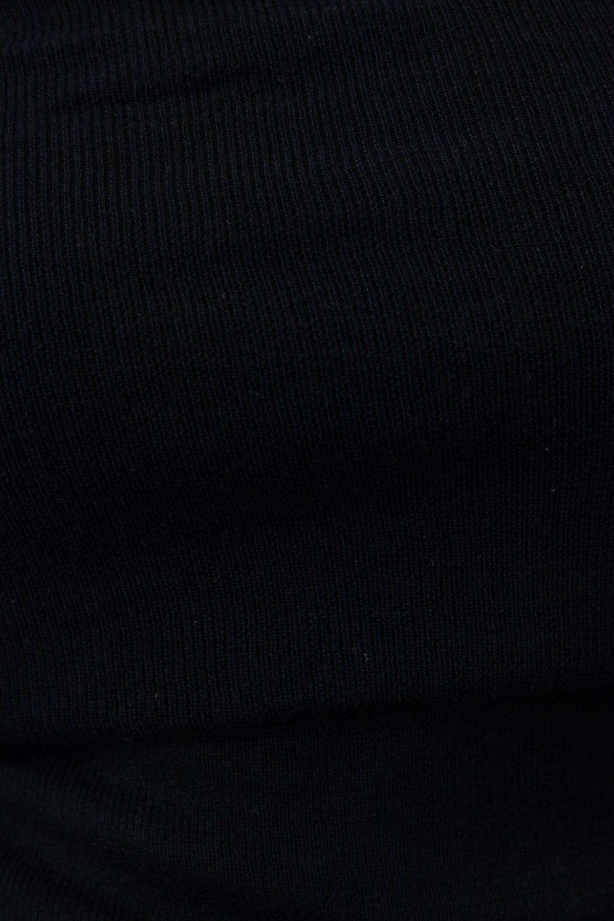 Close-up of ribbed knit black fabric, showcasing texture ideal for a stylish off-shoulder top.