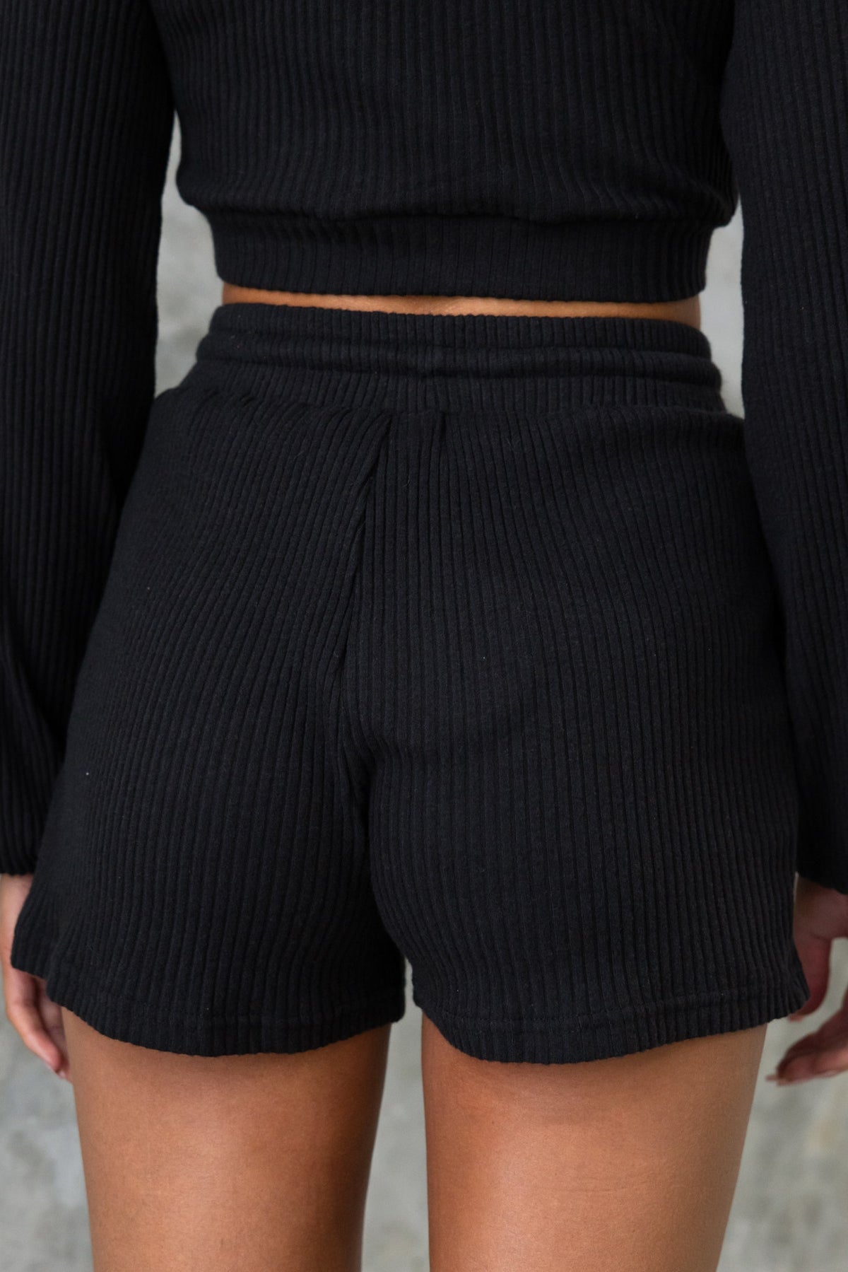 Back view of Mehki black ribbed shorts with mid-high waist and elastic waistband.