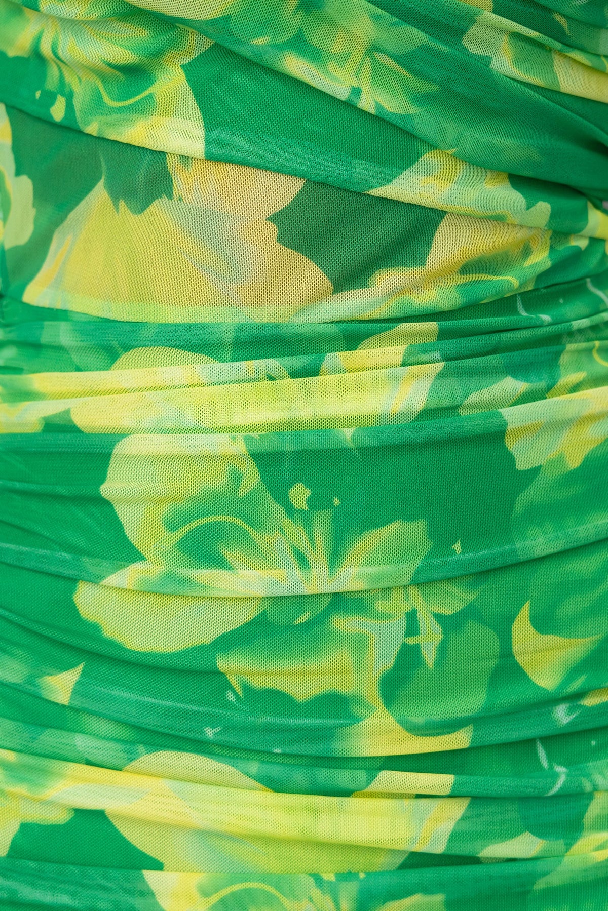 Close-up of soft green fabric with vibrant yellow floral print, showcasing texture and design details.
