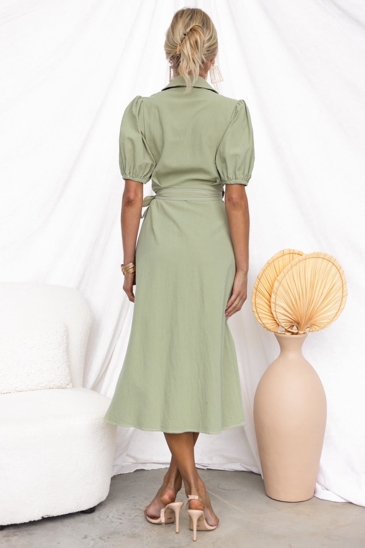 Back view of a woman wearing a Sharnee Wrap Midi Dress in light green with puff sleeves and an asymmetric hem.