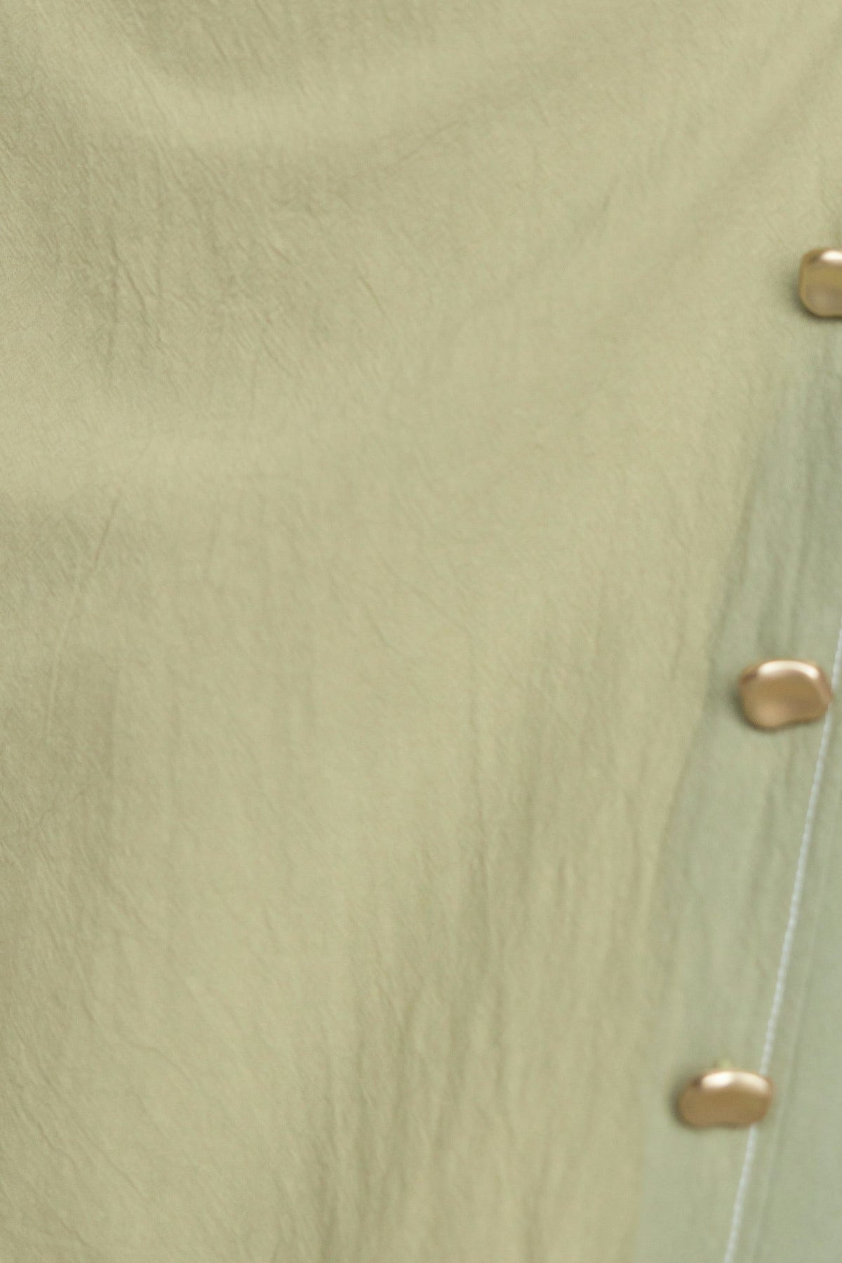 Close-up of light green fabric with faux buttons, showcasing the texture and detail of the Sharnee Wrap Midi Dress.