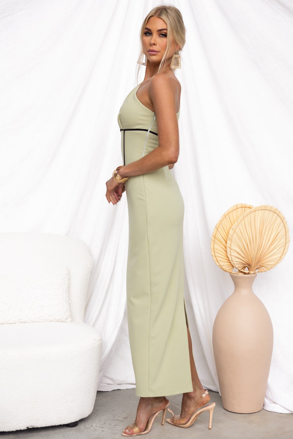 Model wearing a light green Vega Maxi Dress with a one-shoulder neckline and side split, styled elegantly.
