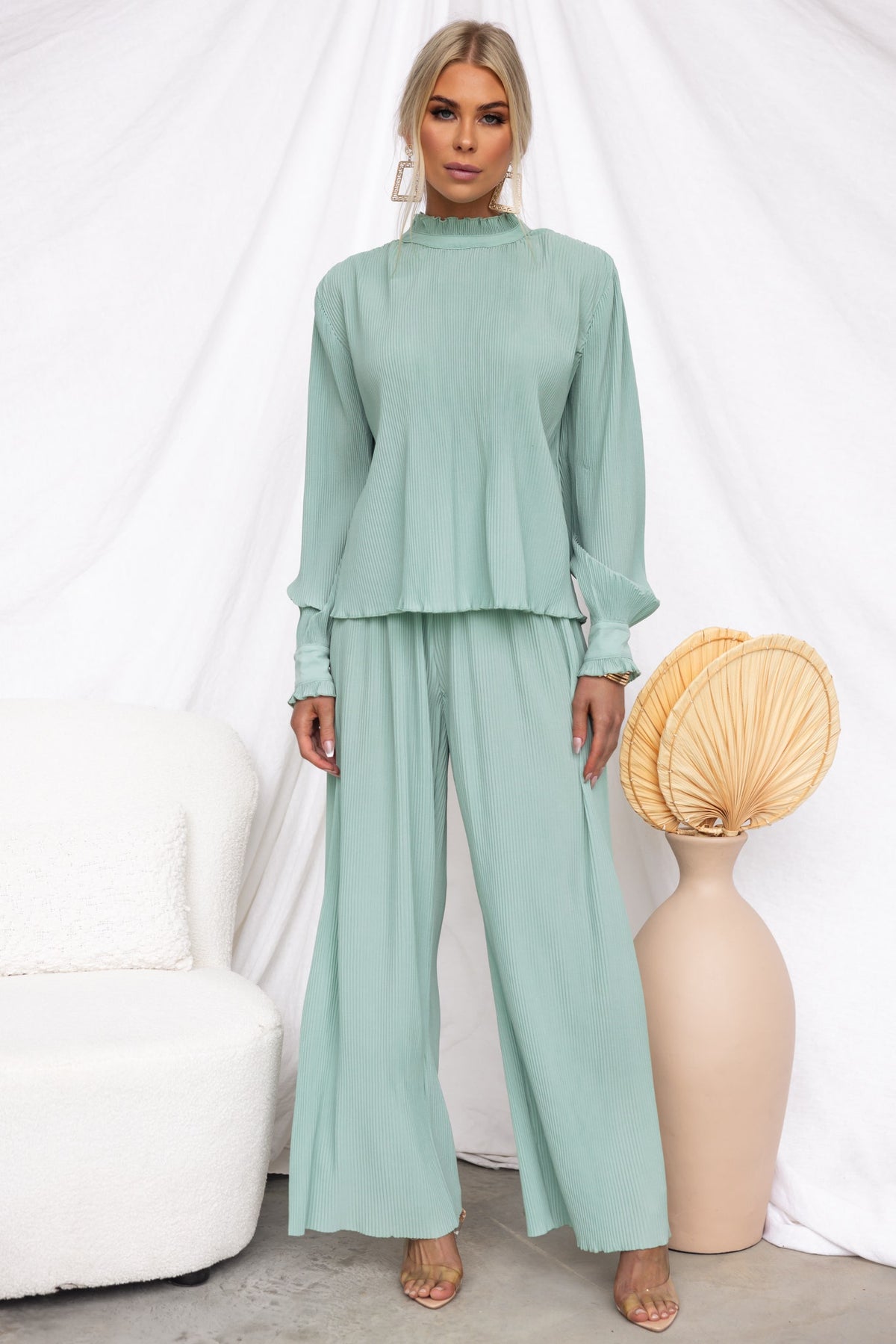 Model wearing a mint green Barbara Top with pleat material and high neckline, styled with matching bottoms.