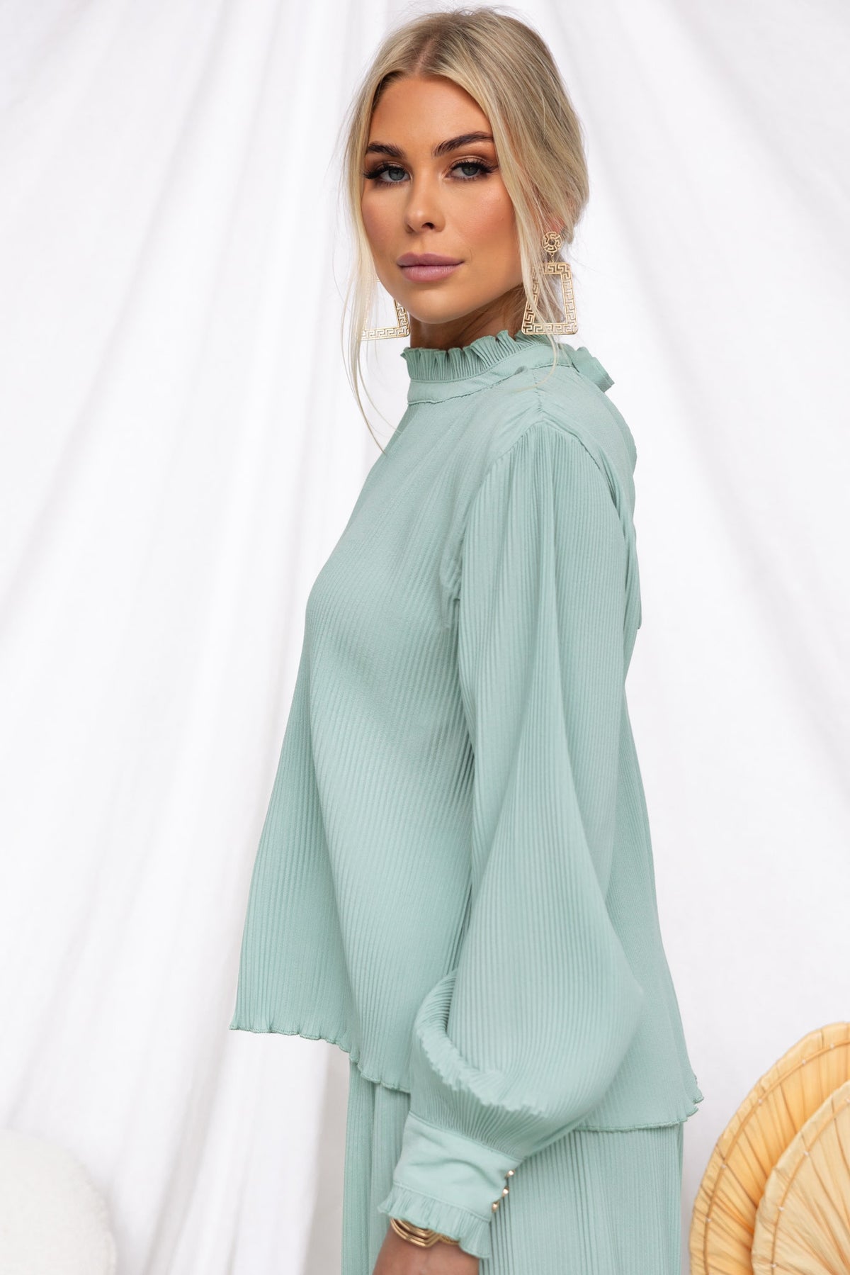 Model wearing the Barbara Top, a high neck pleated mint green blouse with long sleeves and a relaxed fit.