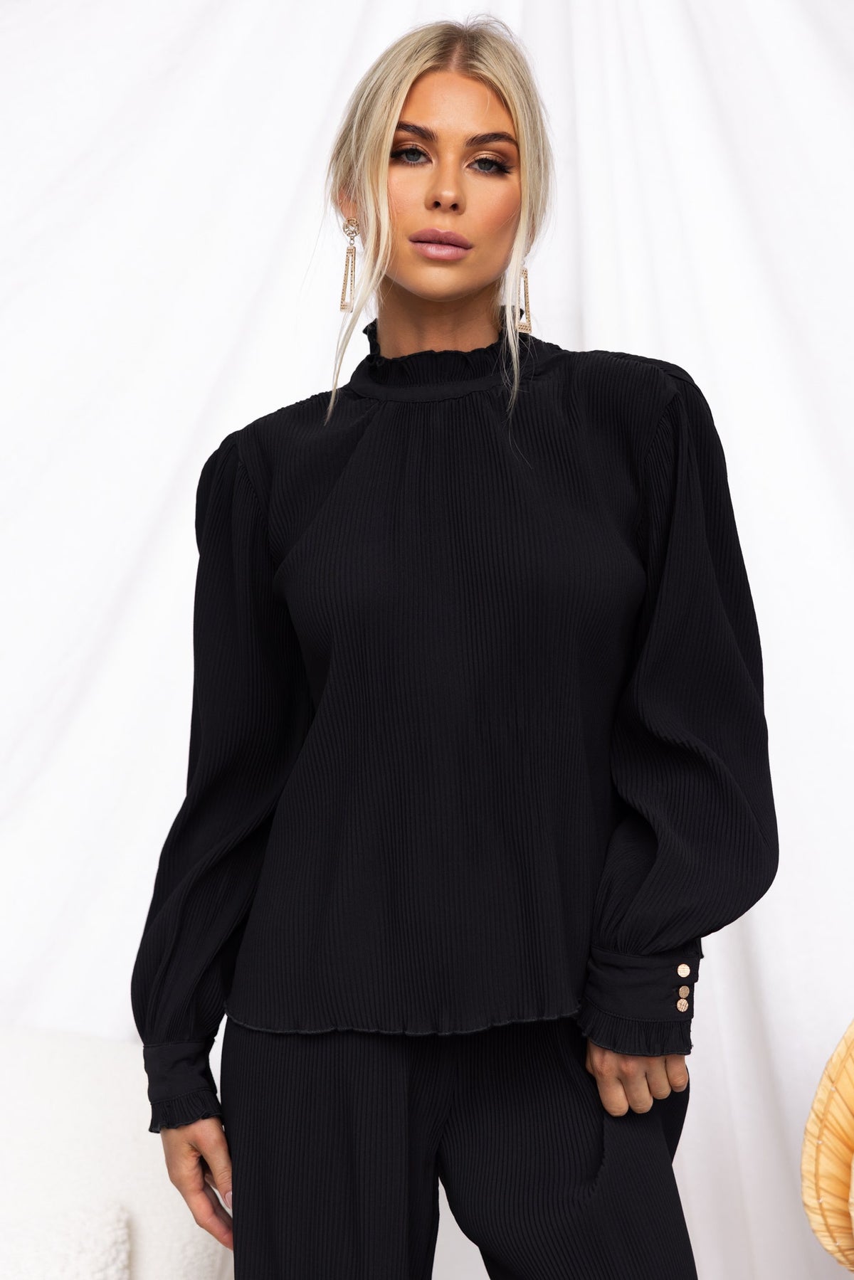 Model wearing Barbara Top, a black high-neck top with pleat material and stylish puff sleeves.