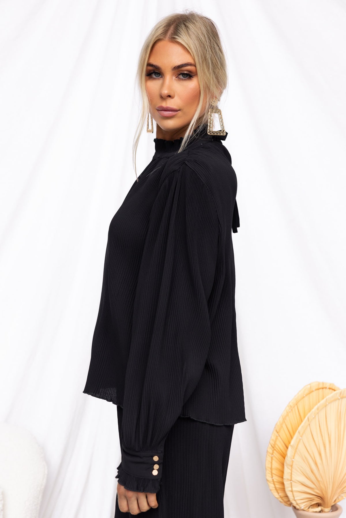 Black Barbara Top with high neckline, tie neck detail, and pleat material, featuring a relaxed fit.