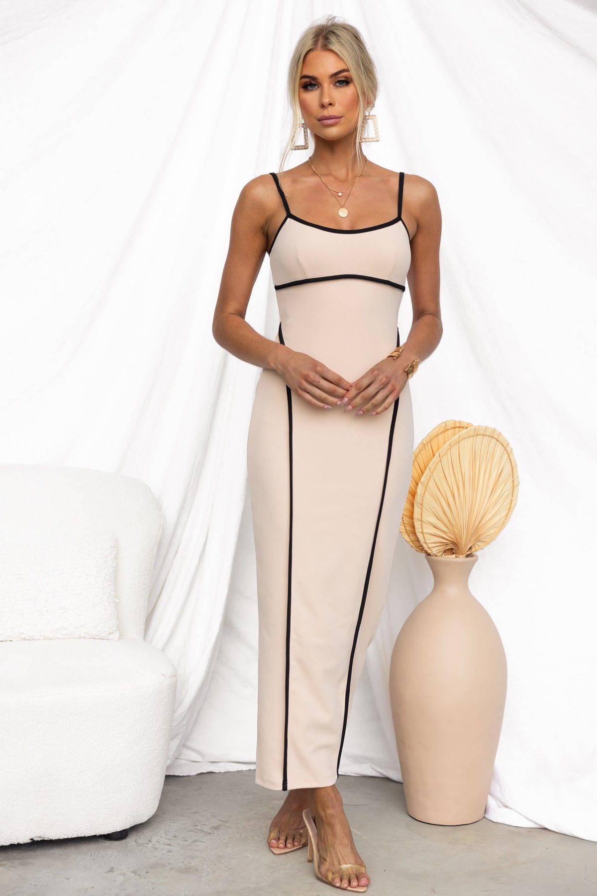 Nabila Maxi Dress with adjustable straps, featuring a sleek silhouette in beige and black accents, displayed in a stylish setting.