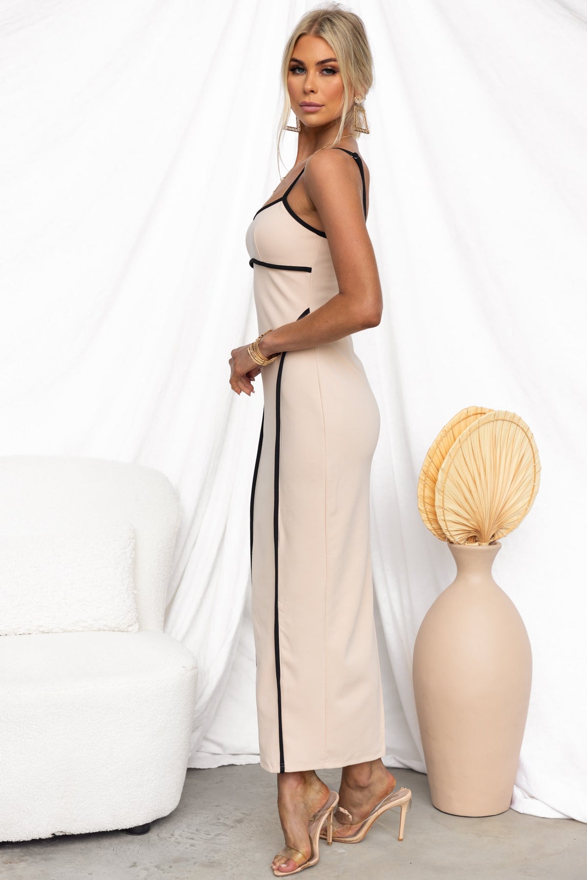 Nabila maxi dress in nude with black trim and adjustable straps, paired with stylish heels, ideal for a chic look.