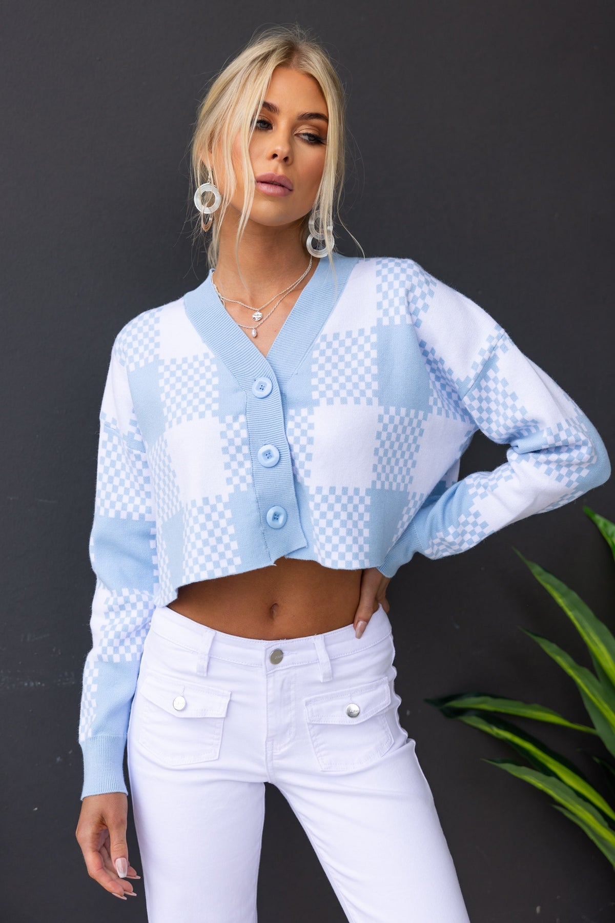 Light blue checkered Roni cardigan with V-neckline, button-up front, and stylish cropped fit worn with white pants.