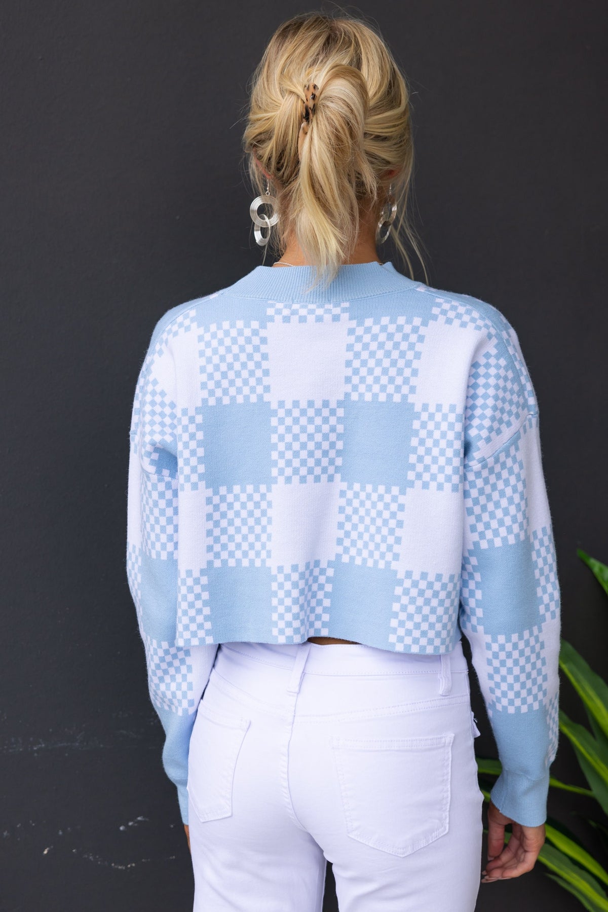 Back view of a blue and white checkered cardigan styled with white jeans.