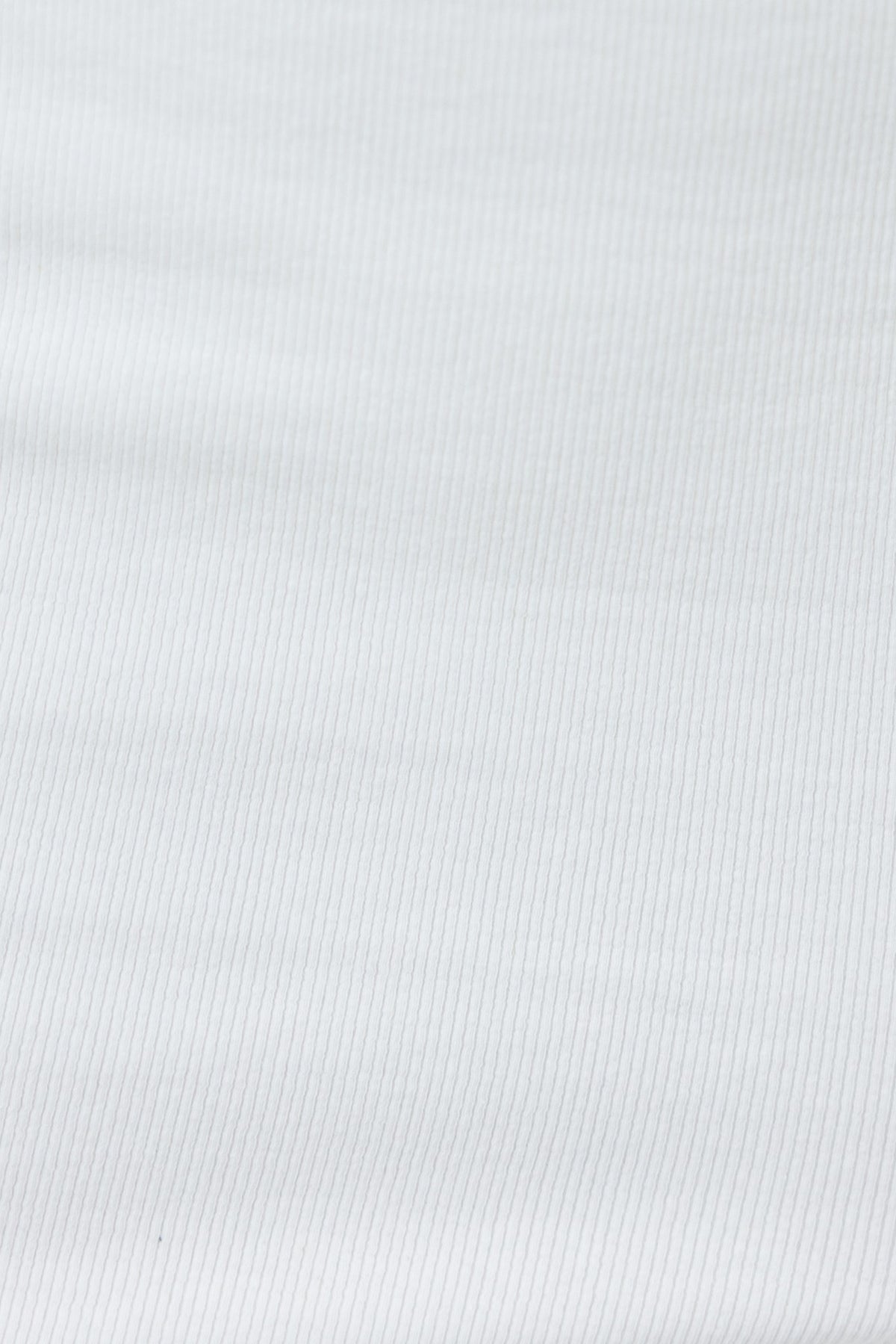 Close-up of ribbed white fabric, ideal for the Carry Me Top, showcasing its soft texture and stretch material.