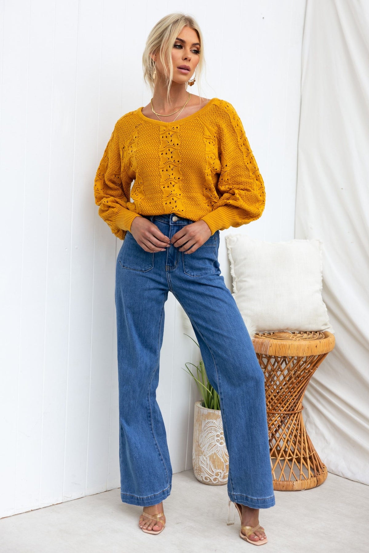 Model wearing a yellow knit top with a V-neckline and relaxed fit paired with high-waisted denim jeans.