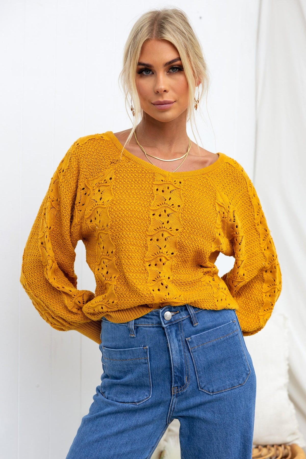 Cadie Knit top in mustard color, featuring a V-neckline and semi-open weave design, styled with high-waisted jeans.