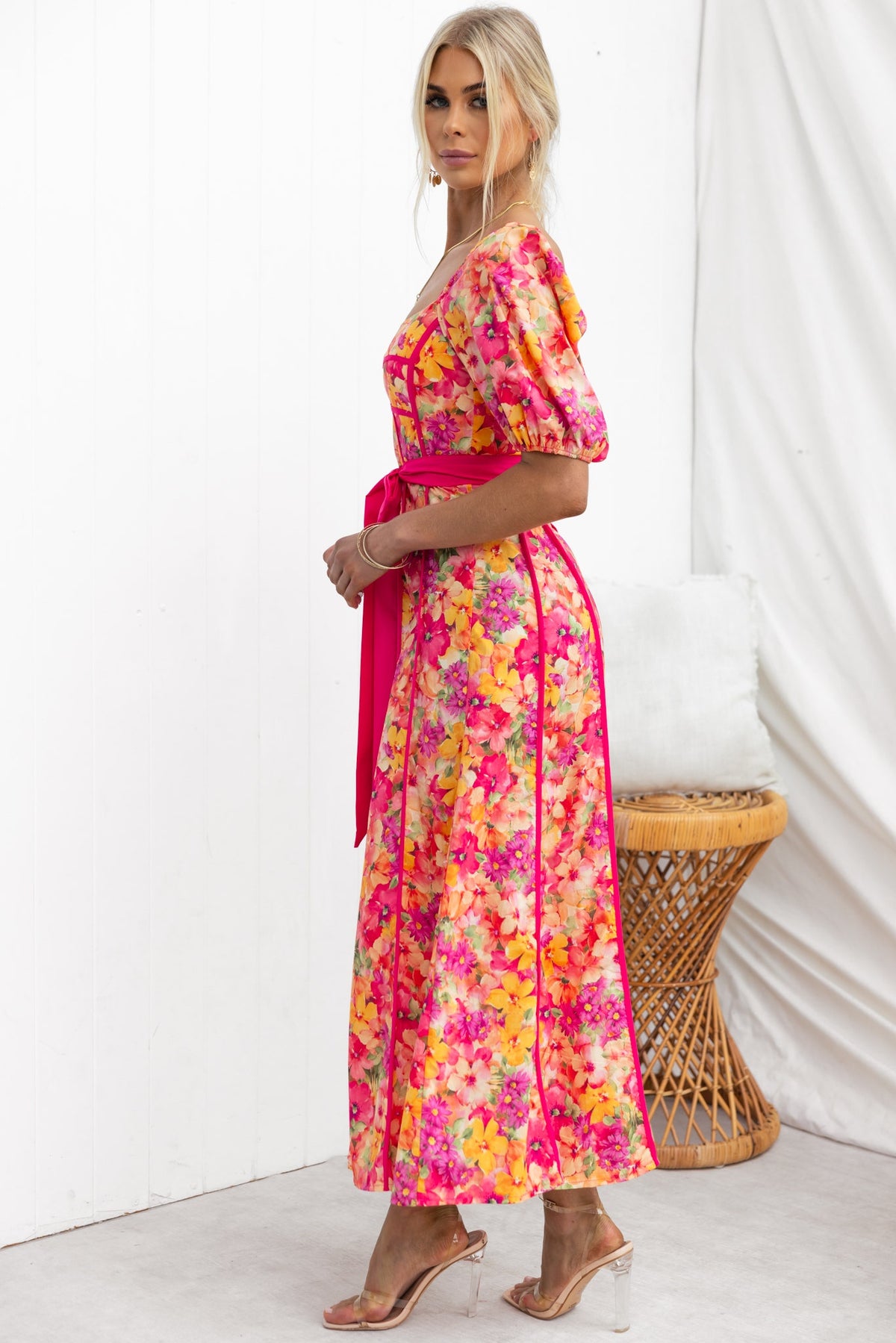 Model wearing the Astoria Maxi Dress, featuring colorful floral print, puff sleeves, and a removable tie belt.