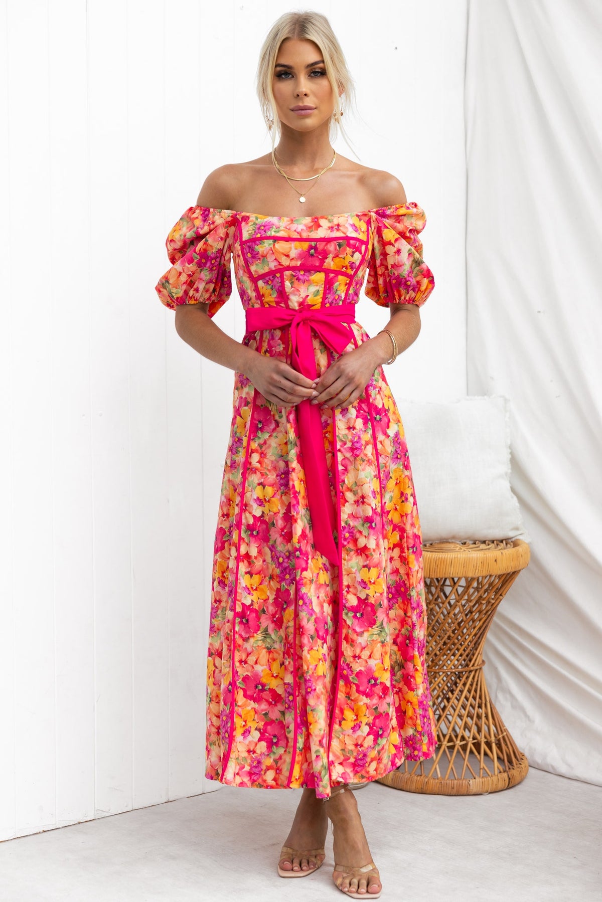 Model wearing bright floral Astoria Maxi Dress with off-shoulder sleeves and removable tie, perfect for summer occasions.