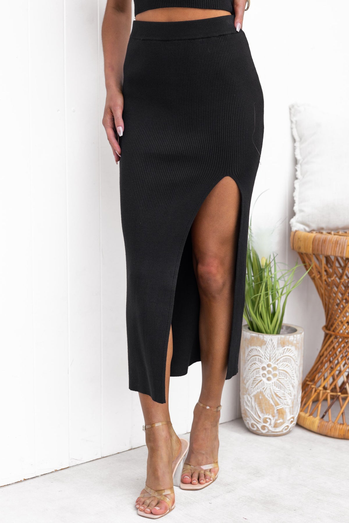 Estha Maxi Skirt in black with front split, ribbed fabric, and elastic waistband, modeled by a woman.