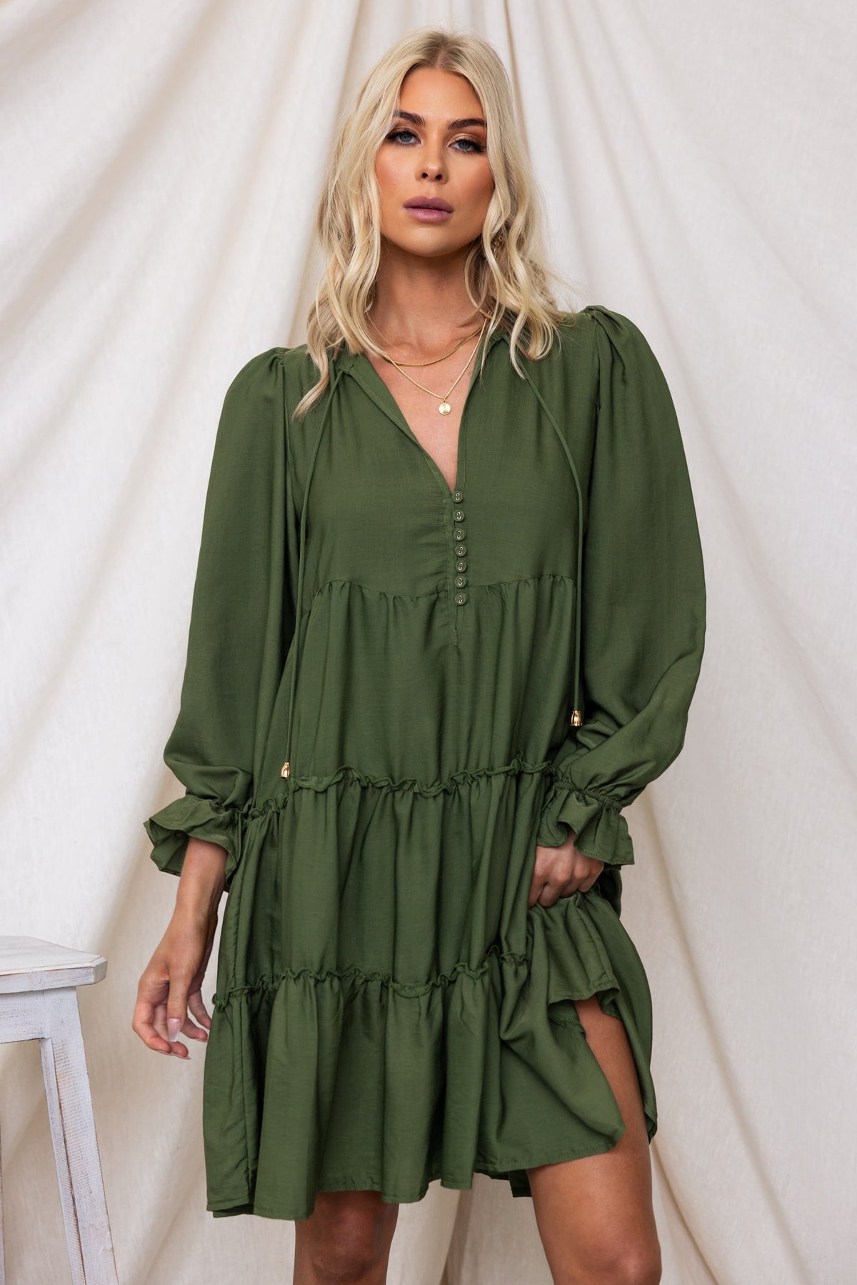 Boone Dress in olive green featuring a V-neckline, tie detail, and relaxed fit with tiered ruffles, perfect for a casual look.