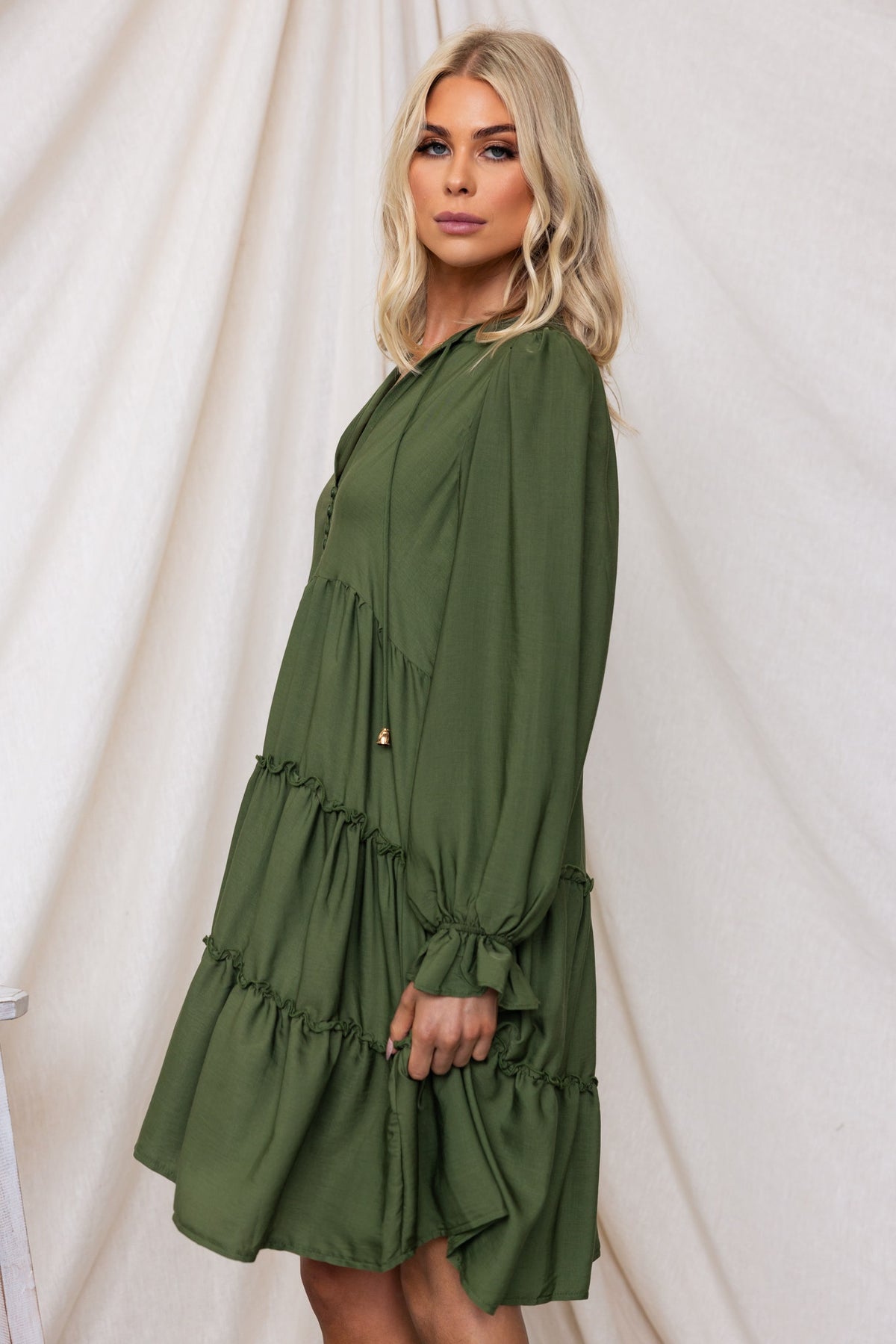 Model wearing the Boone Dress in olive green with V-neckline and tiered design.