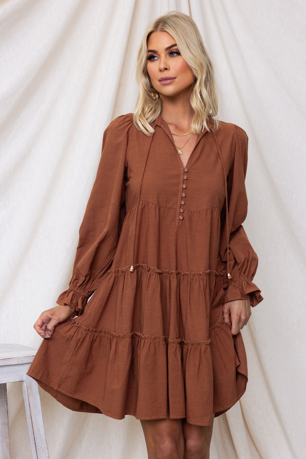Boone Dress featuring V-neckline, button-up front, tie detail, and relaxed fit in rich brown color.