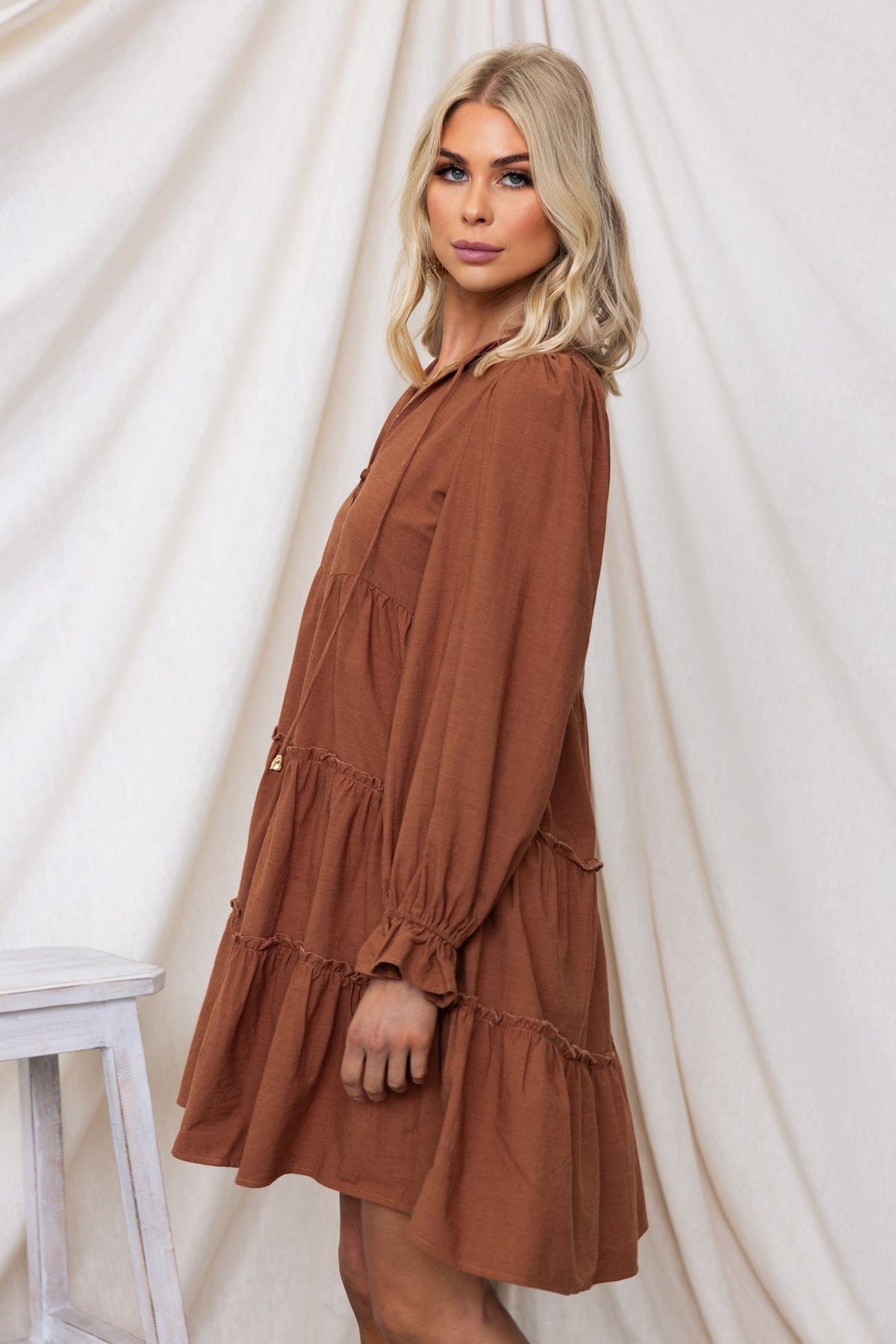 Boone Dress in rust color with V-neckline and button-up front, featuring elastic sleeves and a relaxed fit.