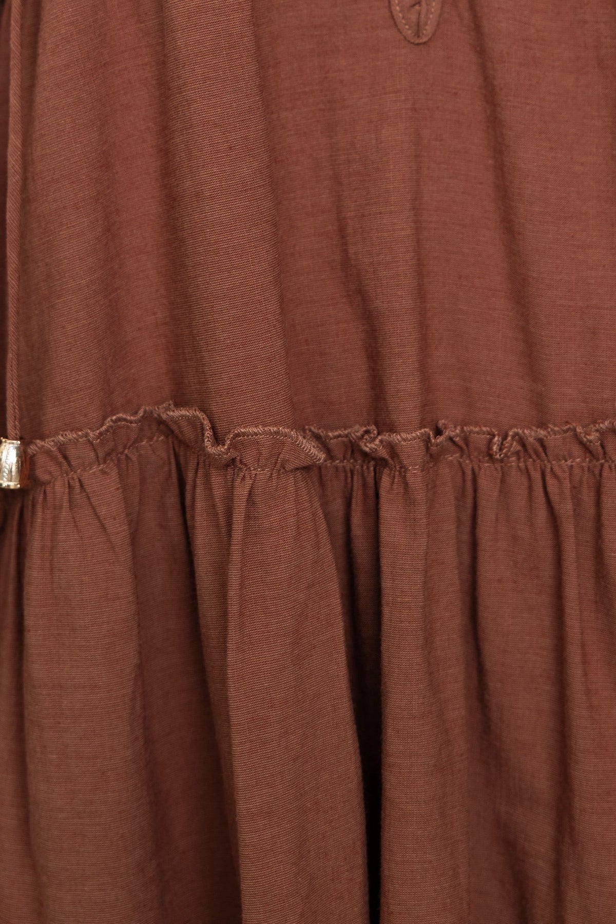 Close-up of the brown Boone Dress showing tie detail and ruffled hem, crafted from cotton and viscose blend.