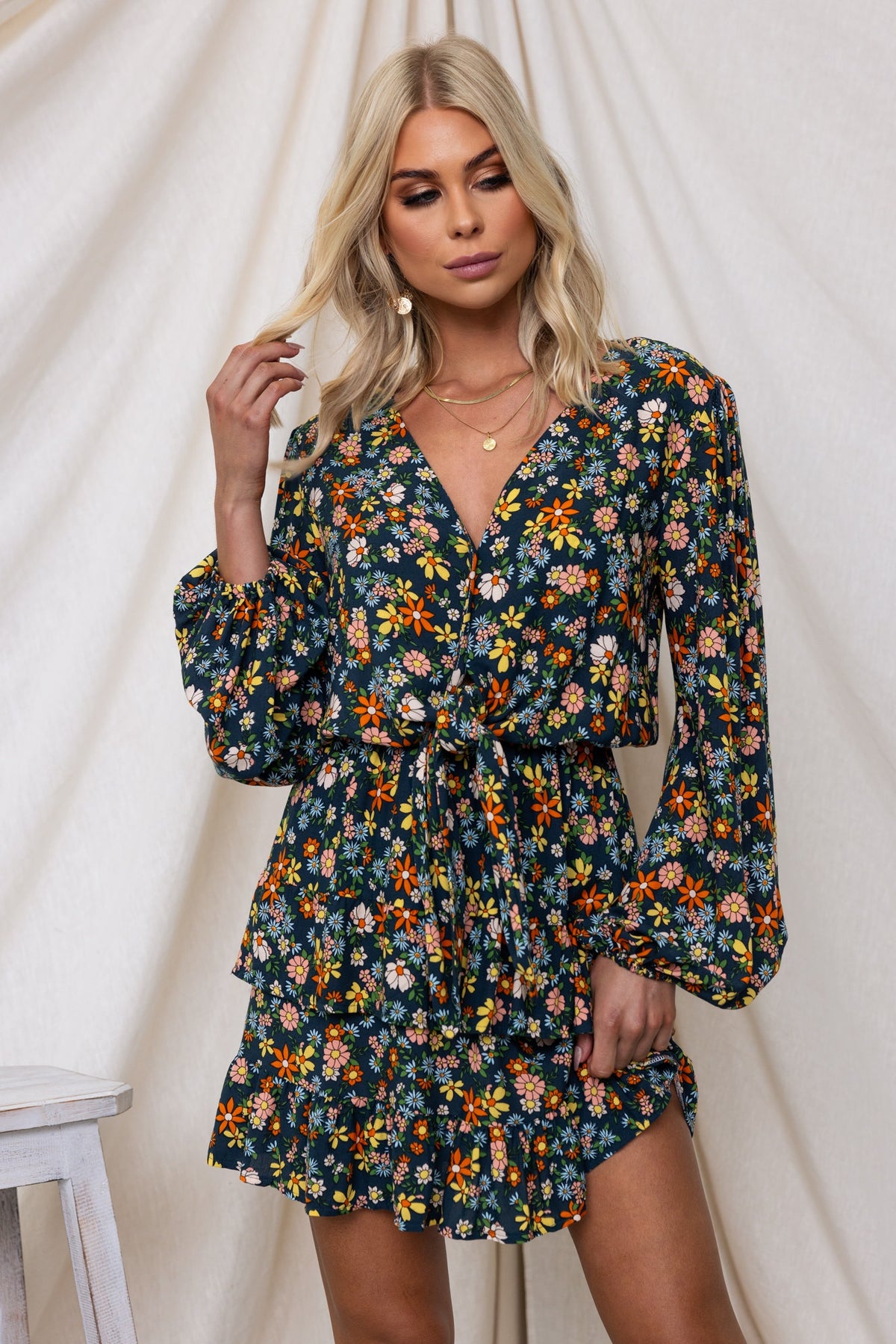 Model wearing a floral navy Lanter Dress with V-neckline and tie at bust, featuring long elastic sleeves and ruffles.