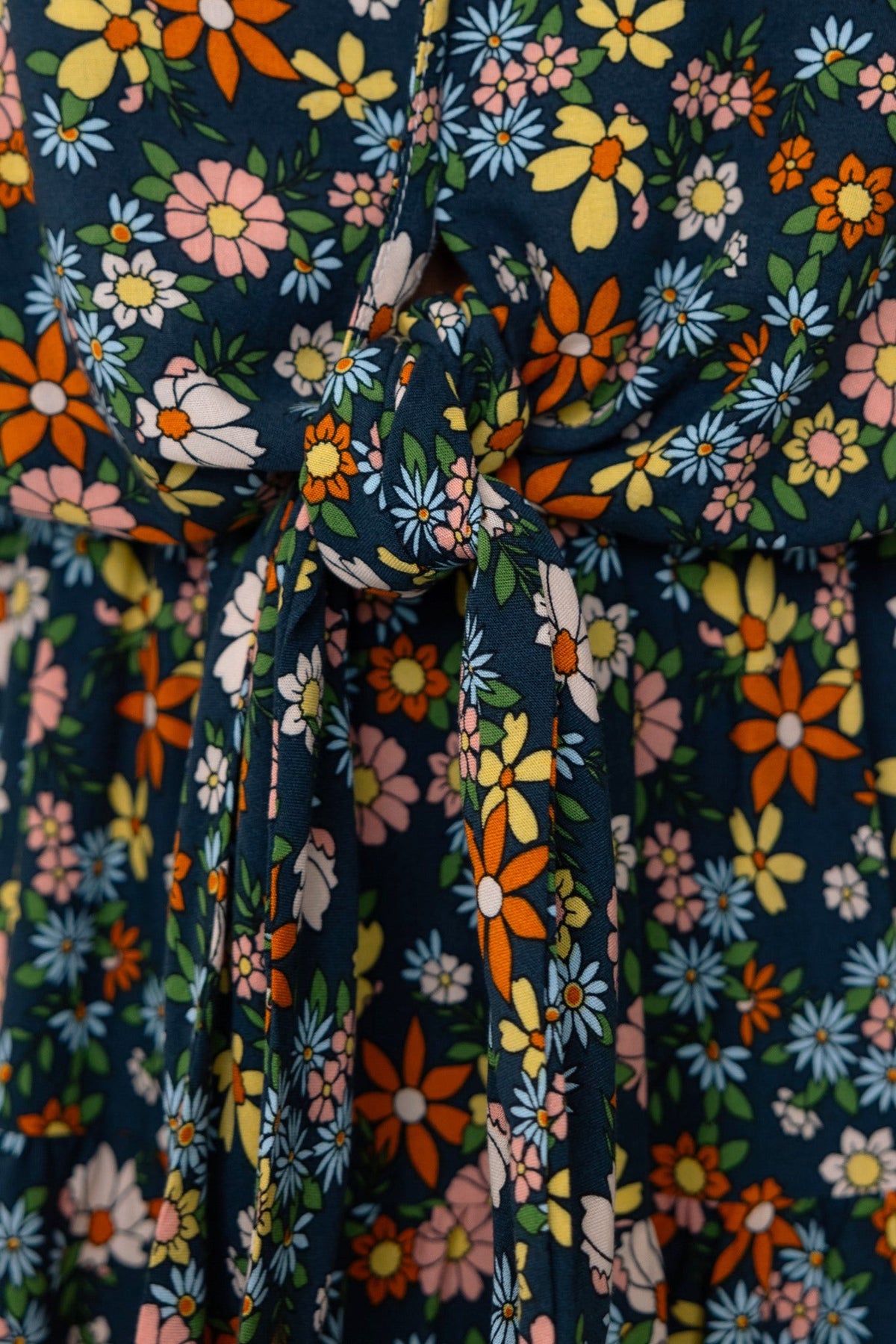 Close-up of the Lanter Dress featuring a floral pattern, v-neckline, and a tie detail at the bust.
